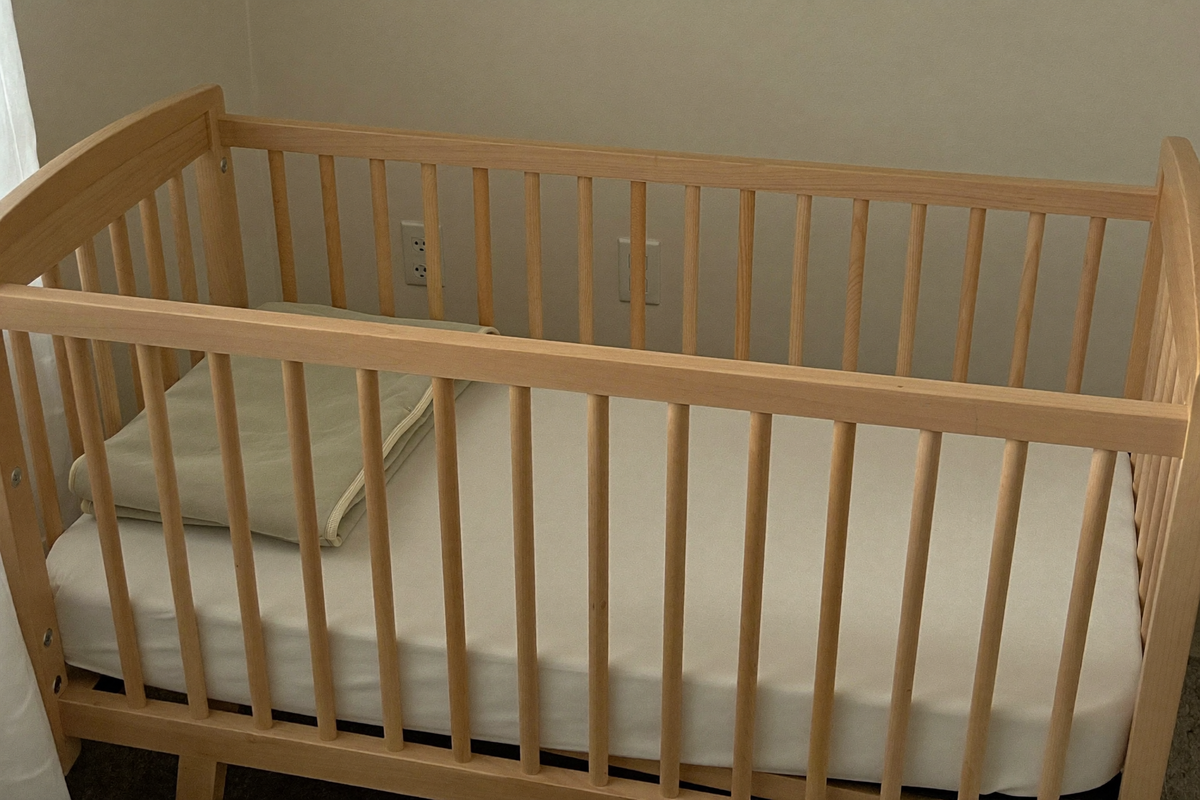 Lit à barreaux vide et correctement préparé : matelas ferme, drap-housse tendu, gigoteuse pliée, rien d'autre dedans Image